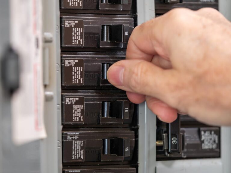 electrician turning off power for electrical outlet