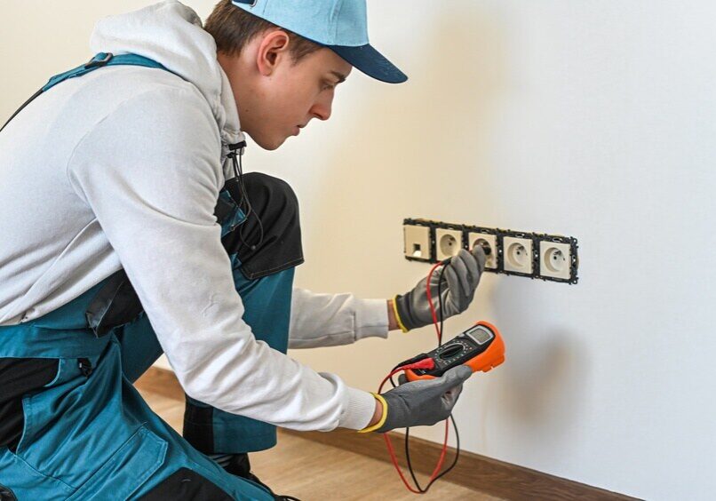 electrician testing wall outlets