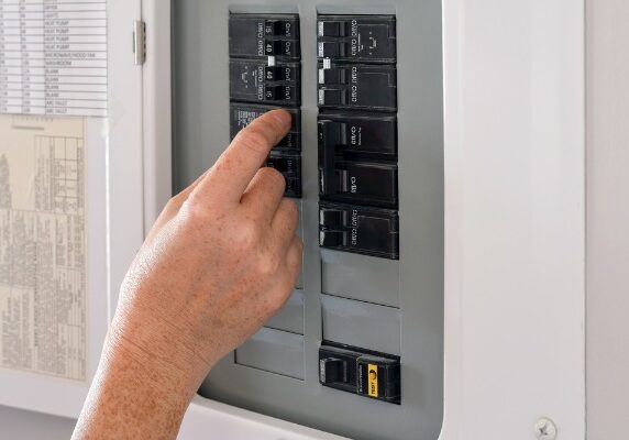 hand flipping a switch on breaker panel