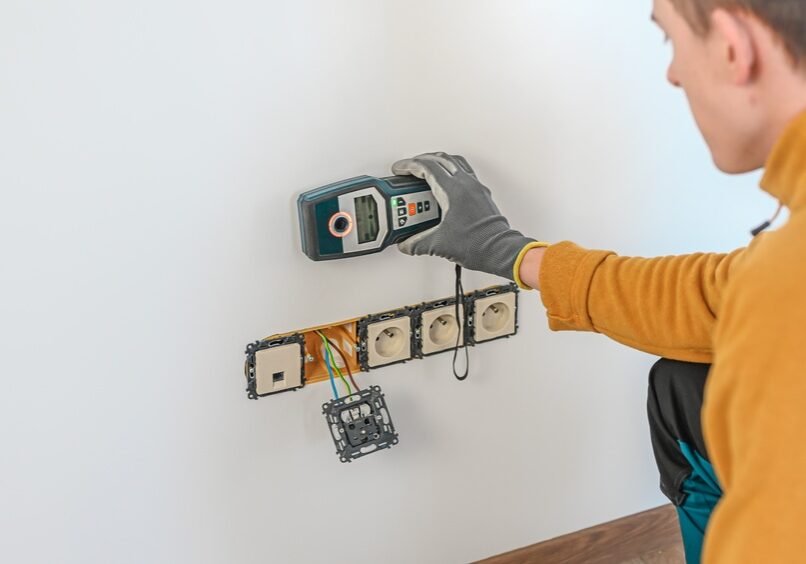 A homeowner plugging an energy monitor into a wall outlet